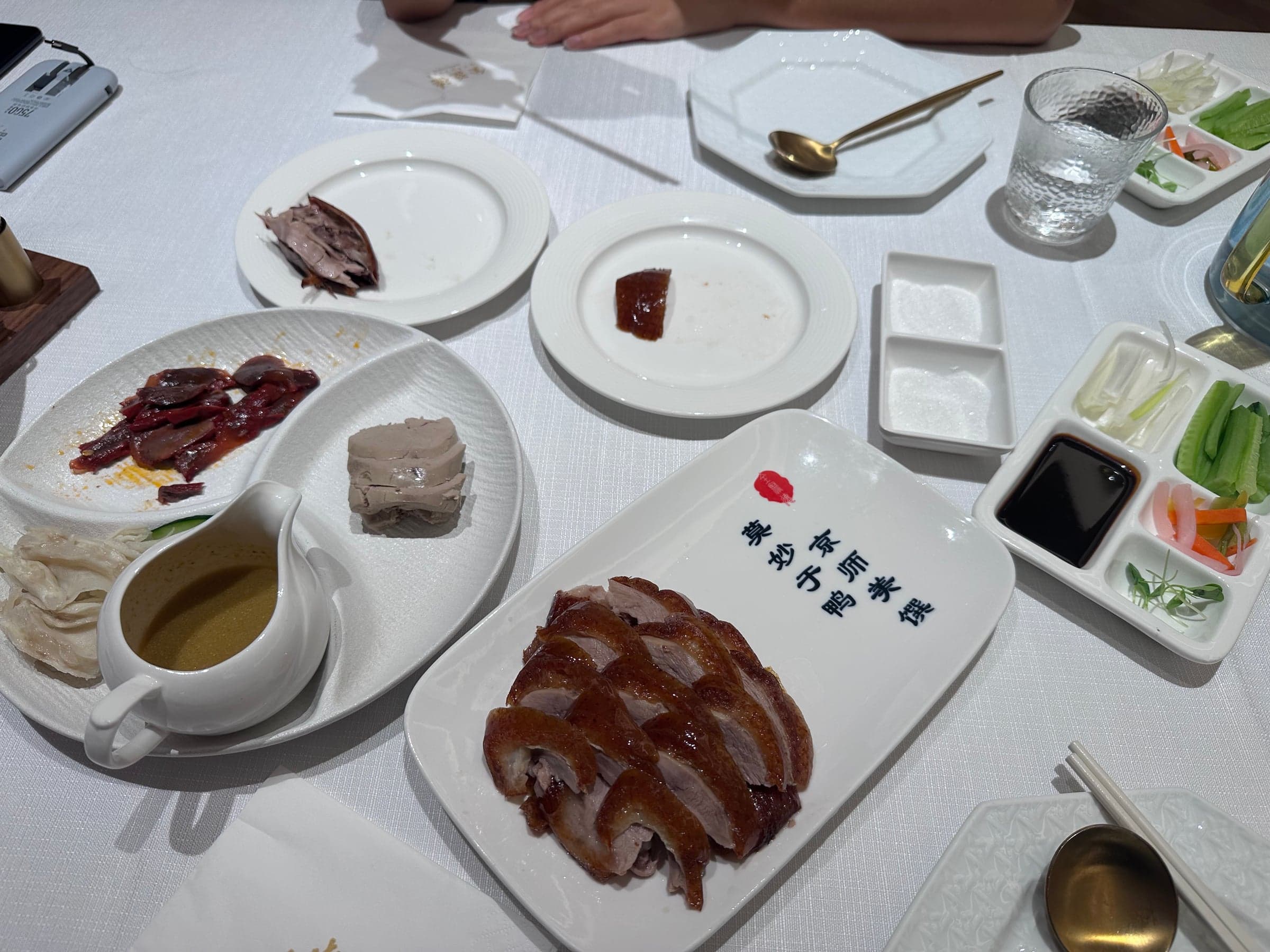 Canard laqué de Pékin découpé sur un plateau, peau croustillante, galettes fines, sauce et bâtonnets de concombre et d'oignon