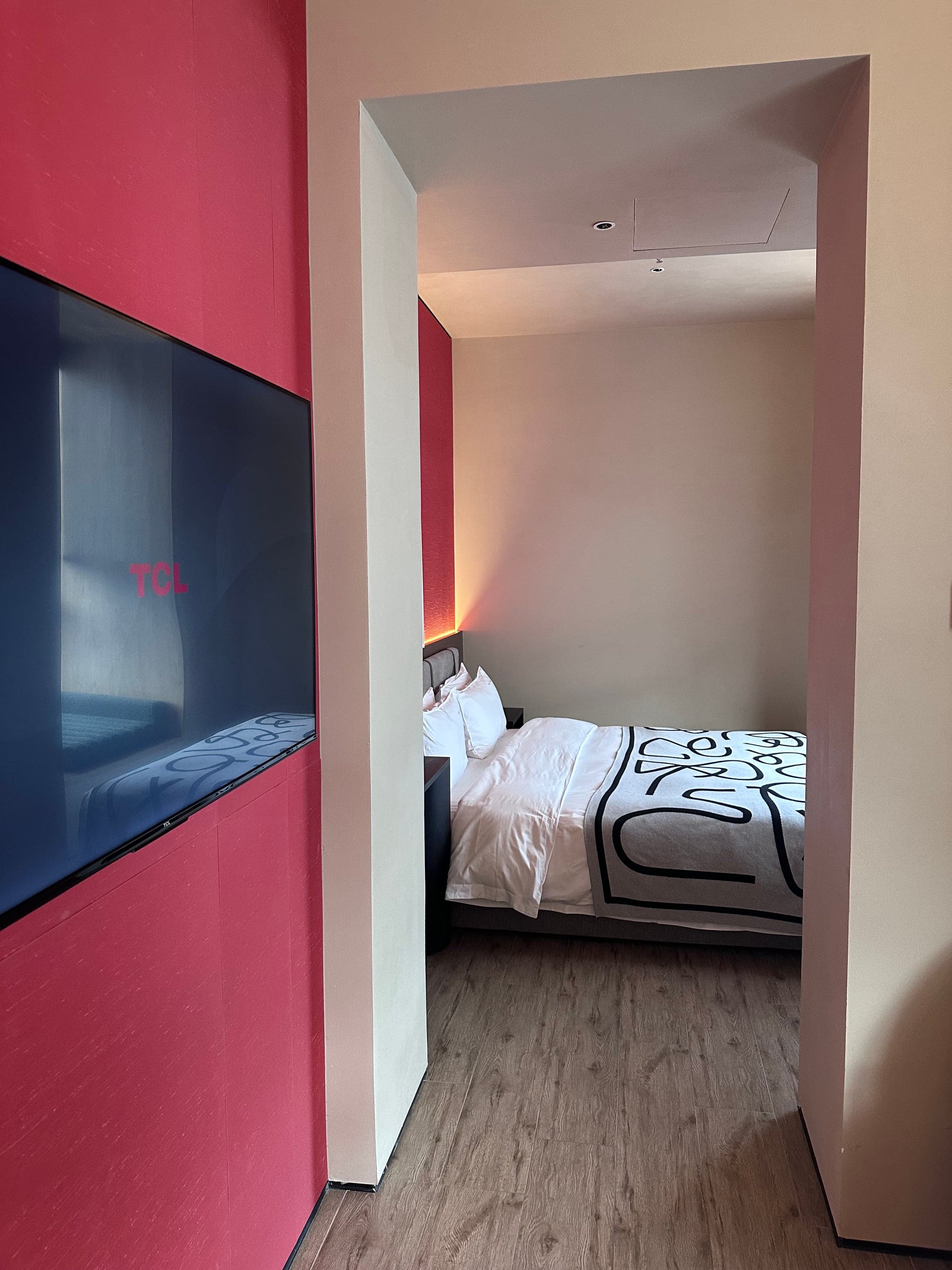 Chambre d'hôtel chinoise atypique sur deux niveaux, couchage en alcôve surélevée et grand écran encastré dans le sol rouge