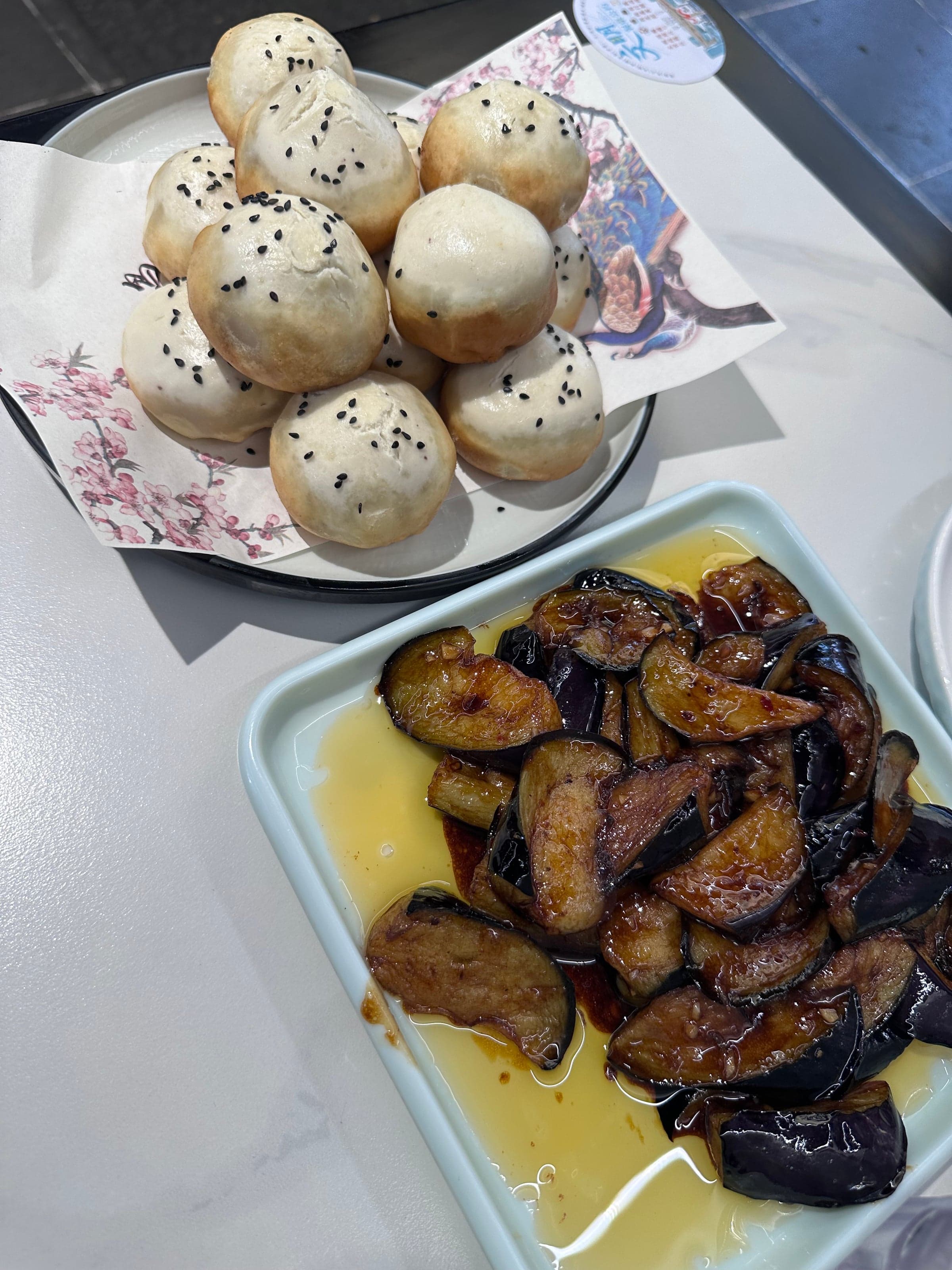Baozi au sésame noir et aubergines laquées sur une table de petit restaurant à Suzhou