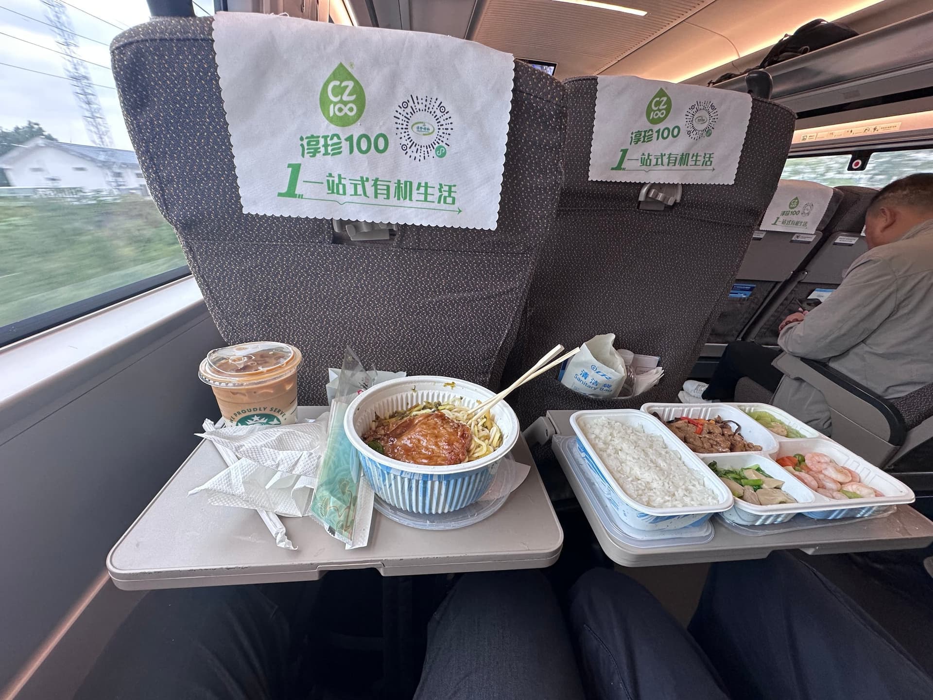 Intérieur d'un train à grande vitesse en Chine, plateau-repas sur tablette de siège avec bol de nouilles, plats de riz et viande, café en gobelet