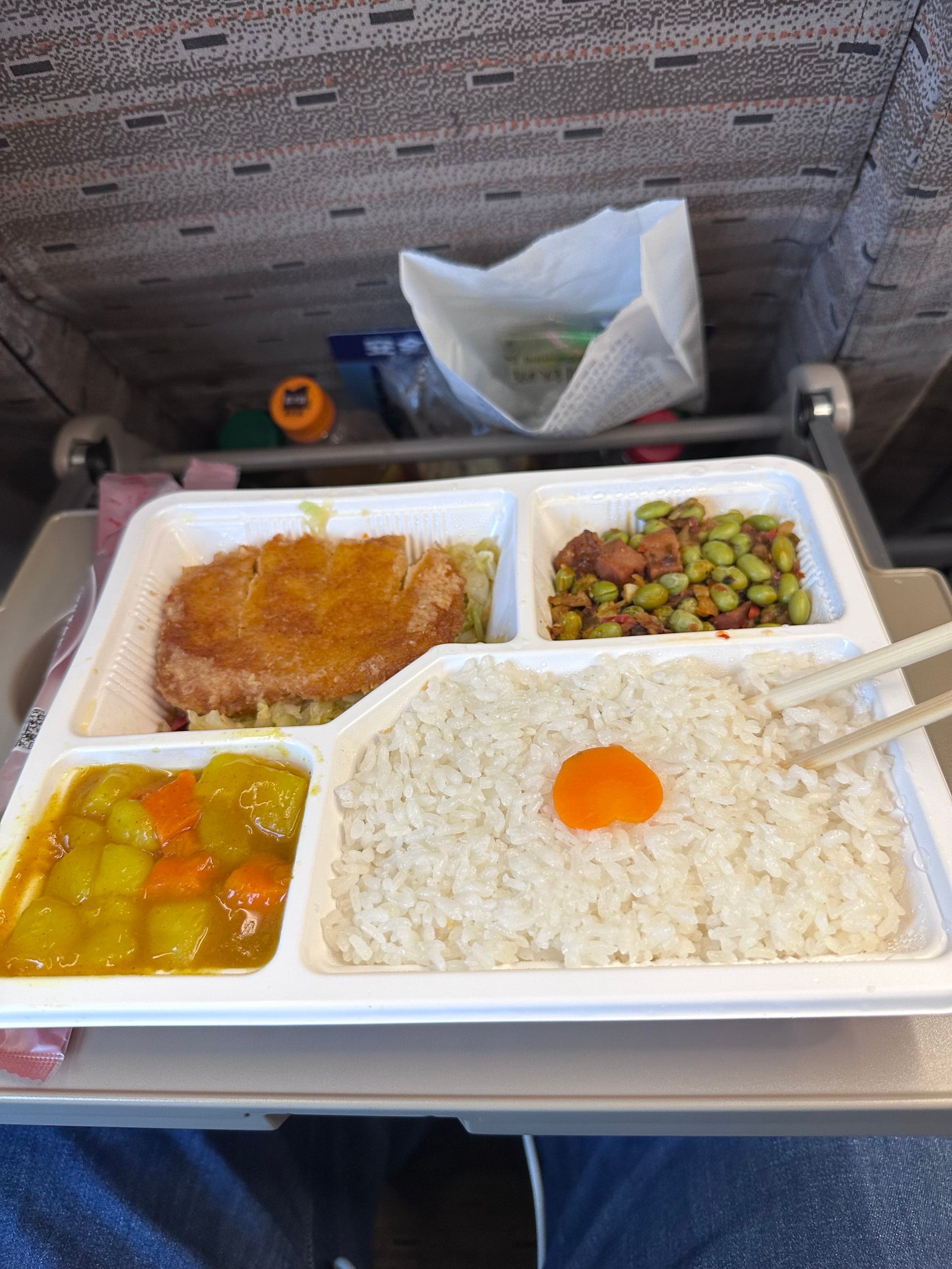 Plateau-repas servi à bord d'un train à grande vitesse chinois : escalope panée, riz blanc, légumes au curry et fèves de soja, sur la tablette du siège
