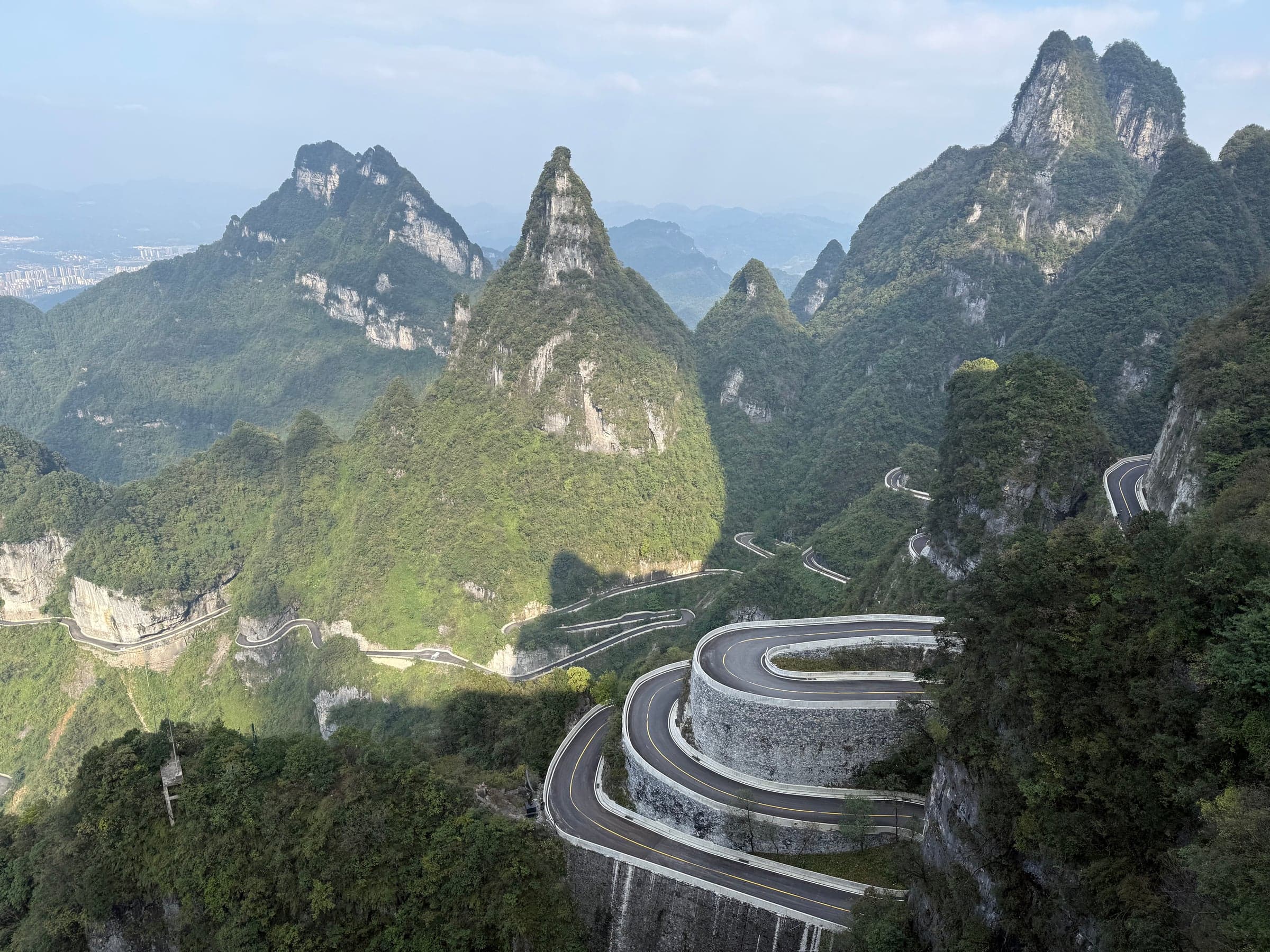 Route de montagne en lacets serrés s'enroulant à flanc de falaise sous les pics de la montagne Tianmen