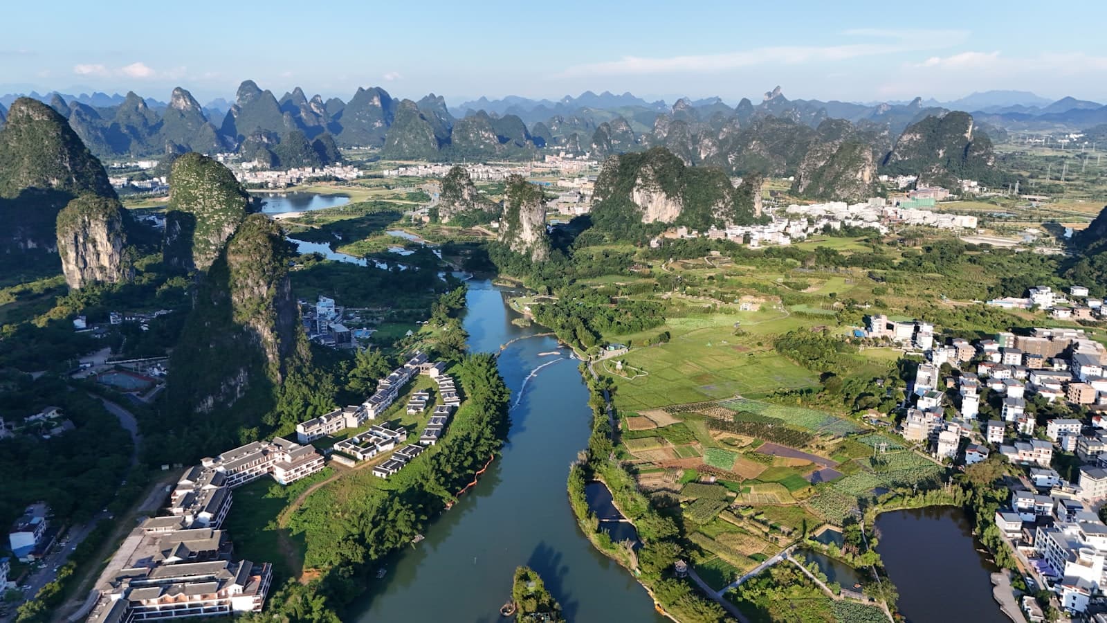 Vue aérienne des pitons karstiques de Guilin et Yangshuo, la rivière serpentant entre les collines calcaires couvertes de végétation, villages et rizières au pied des reliefs