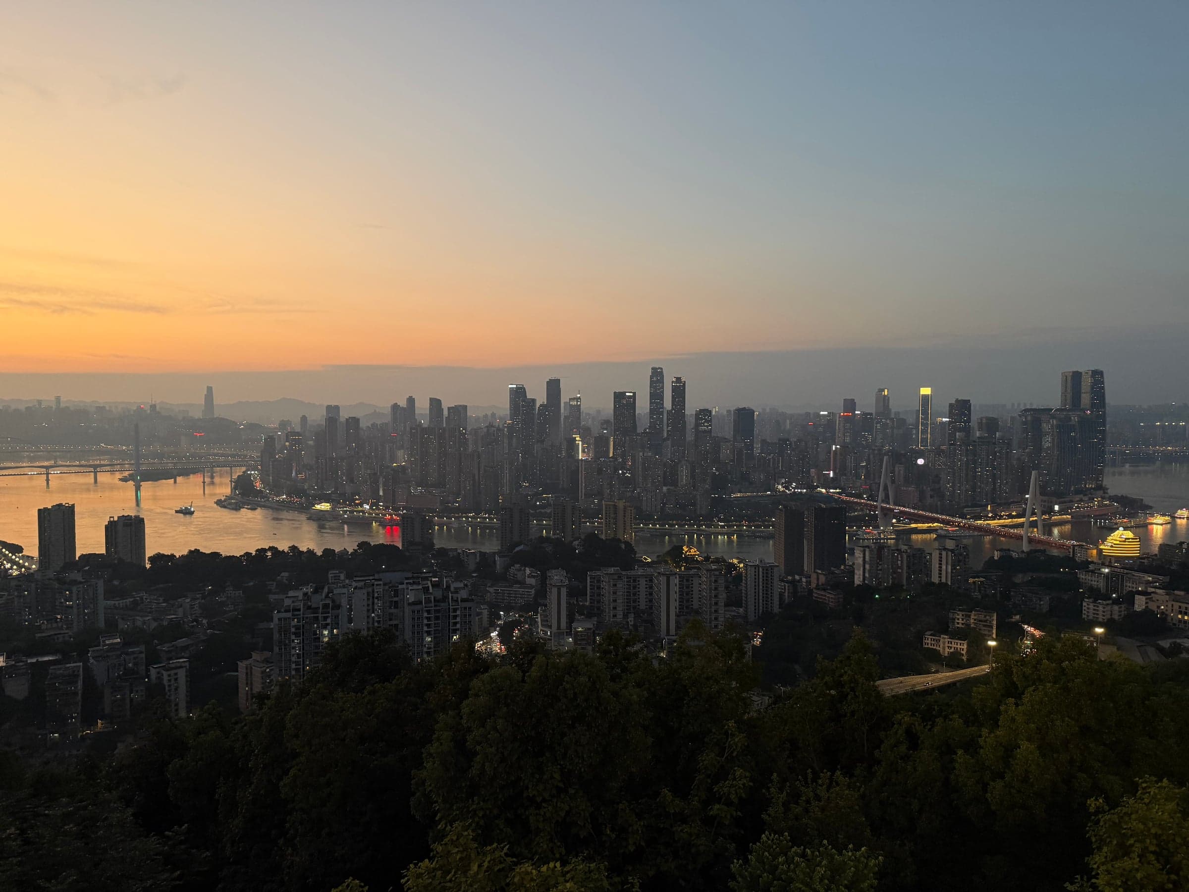 Panoramique sur la skyline de Chongqing au crépuscule, les tours s'illuminent au-dessus du Yangtsé et de ses ponts