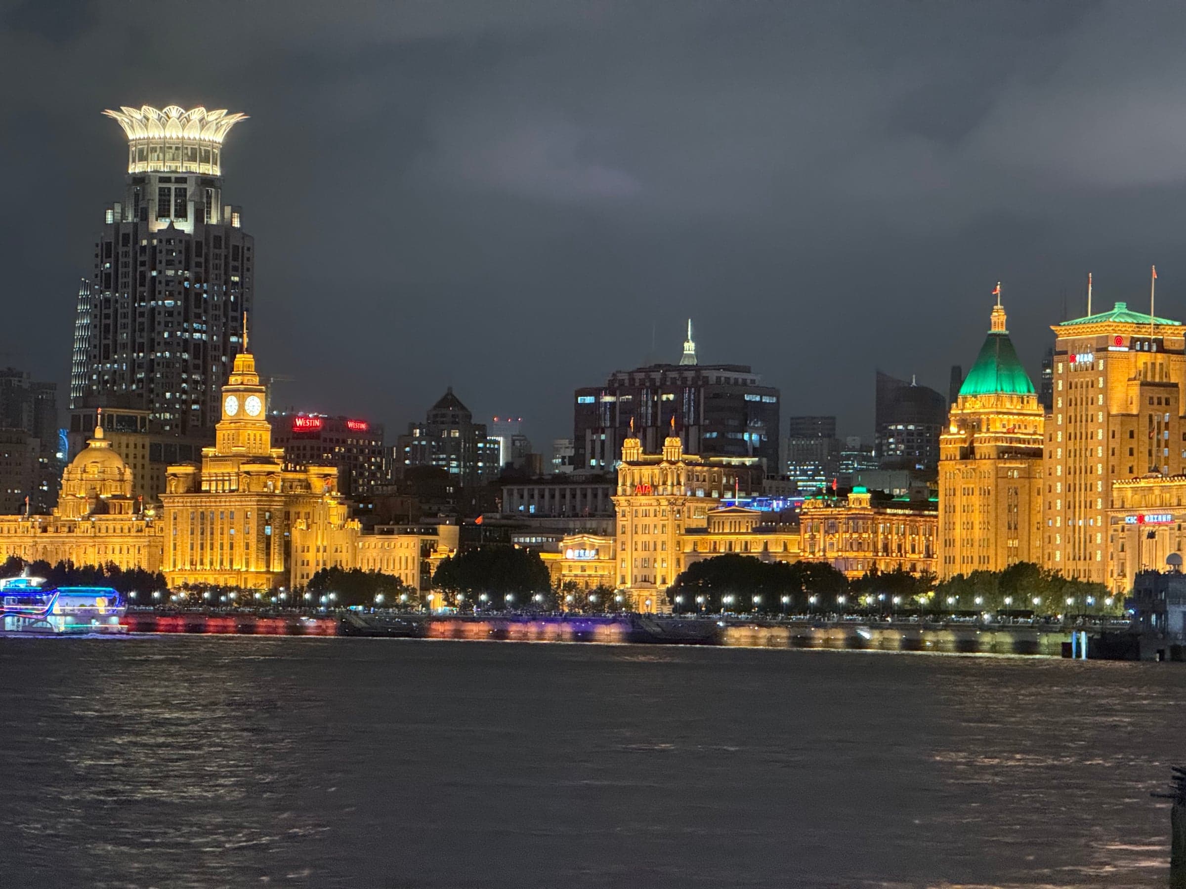 Façades historiques du Bund illuminées en doré la nuit à Shanghai vues depuis le fleuve Huangpu, tour-horloge de la Customs House, dôme de l'ancienne HSBC et toit pyramidal vert du Peace Hotel