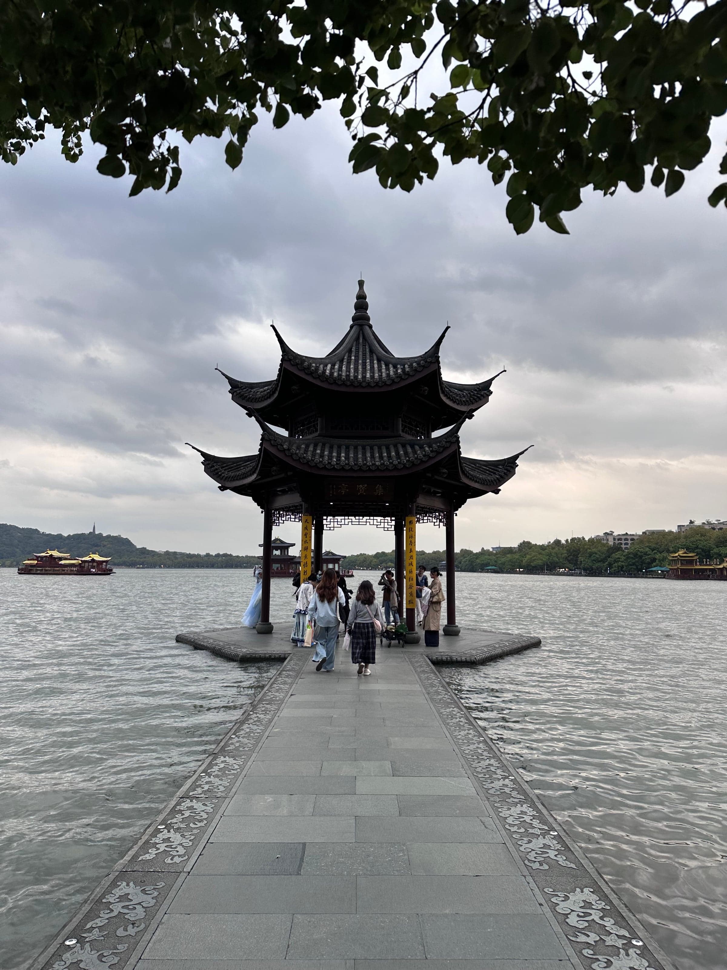 Lac de l'Ouest (Xihu) à Hangzhou, pavillon traditionnel au bord de l'eau, lotus au premier plan, montagnes en arrière-plan