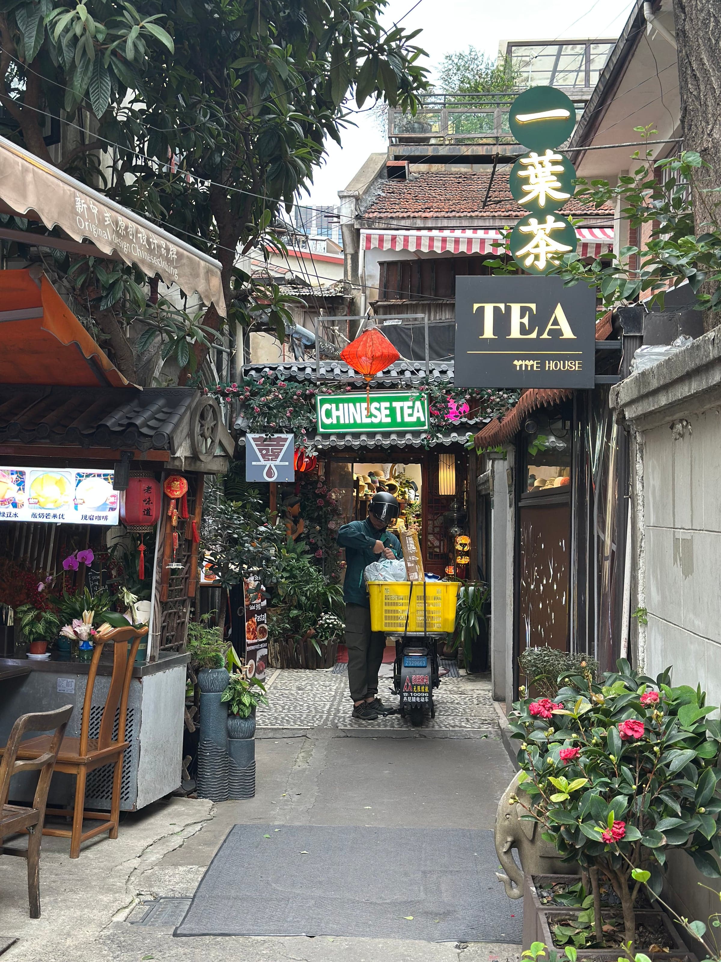 Ruelle étroite de Tianzifang à Shanghai, maison de thé et livreur poussant son scooter chargé