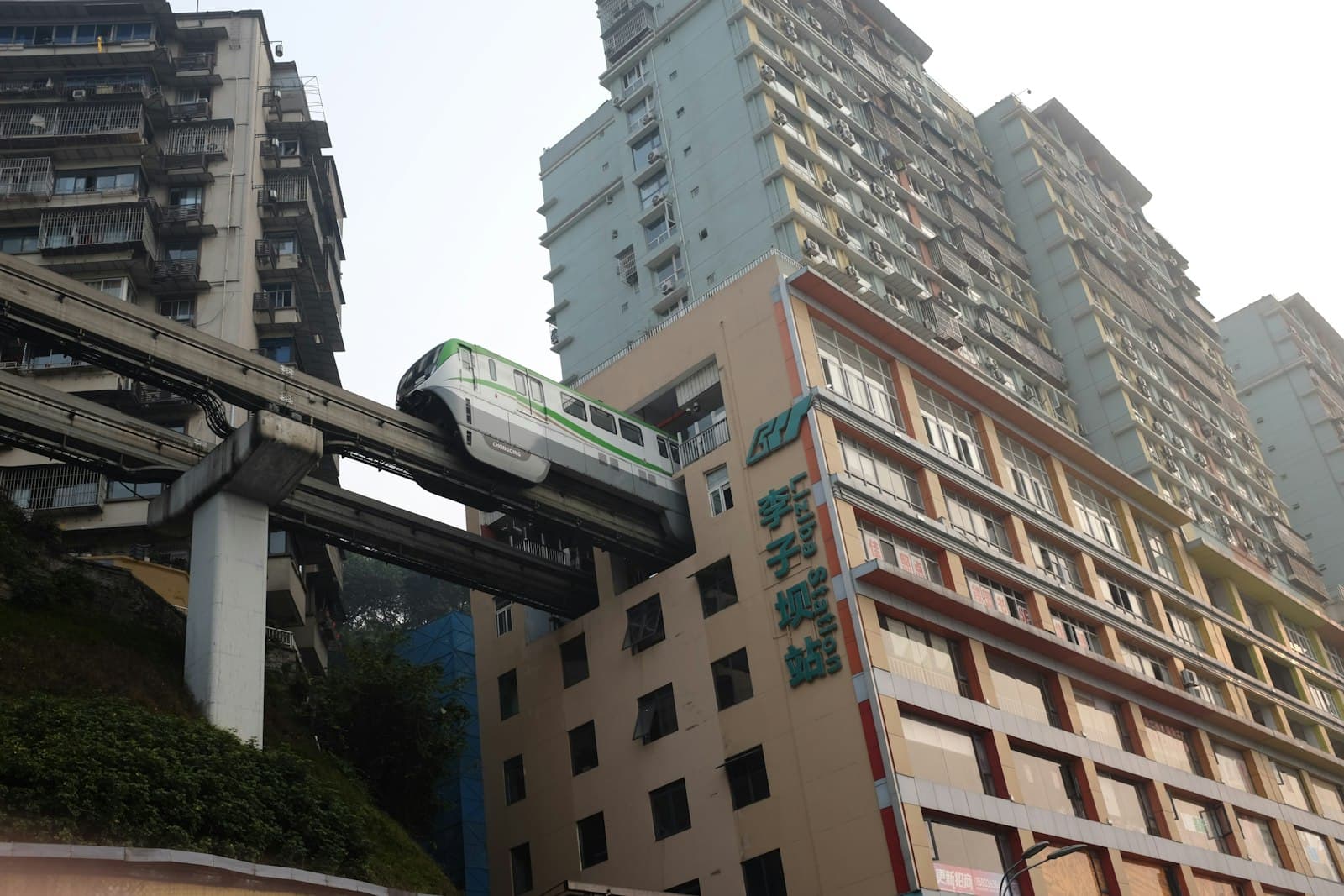Le monorail de la ligne 2 de Chongqing sortant d'un immeuble d'habitation à la station Liziba