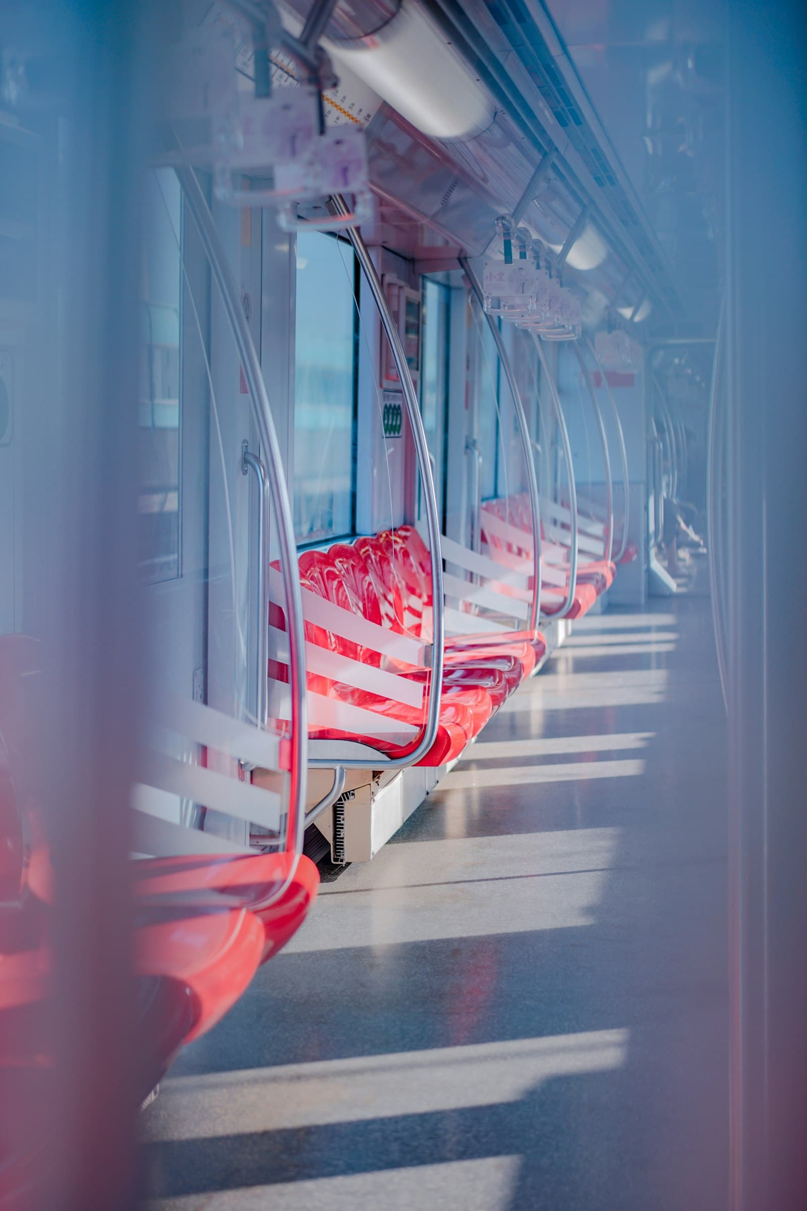 Intérieur d'une rame de métro à Shanghai : sièges rouges vides, barres chromées et sol baigné de lumière