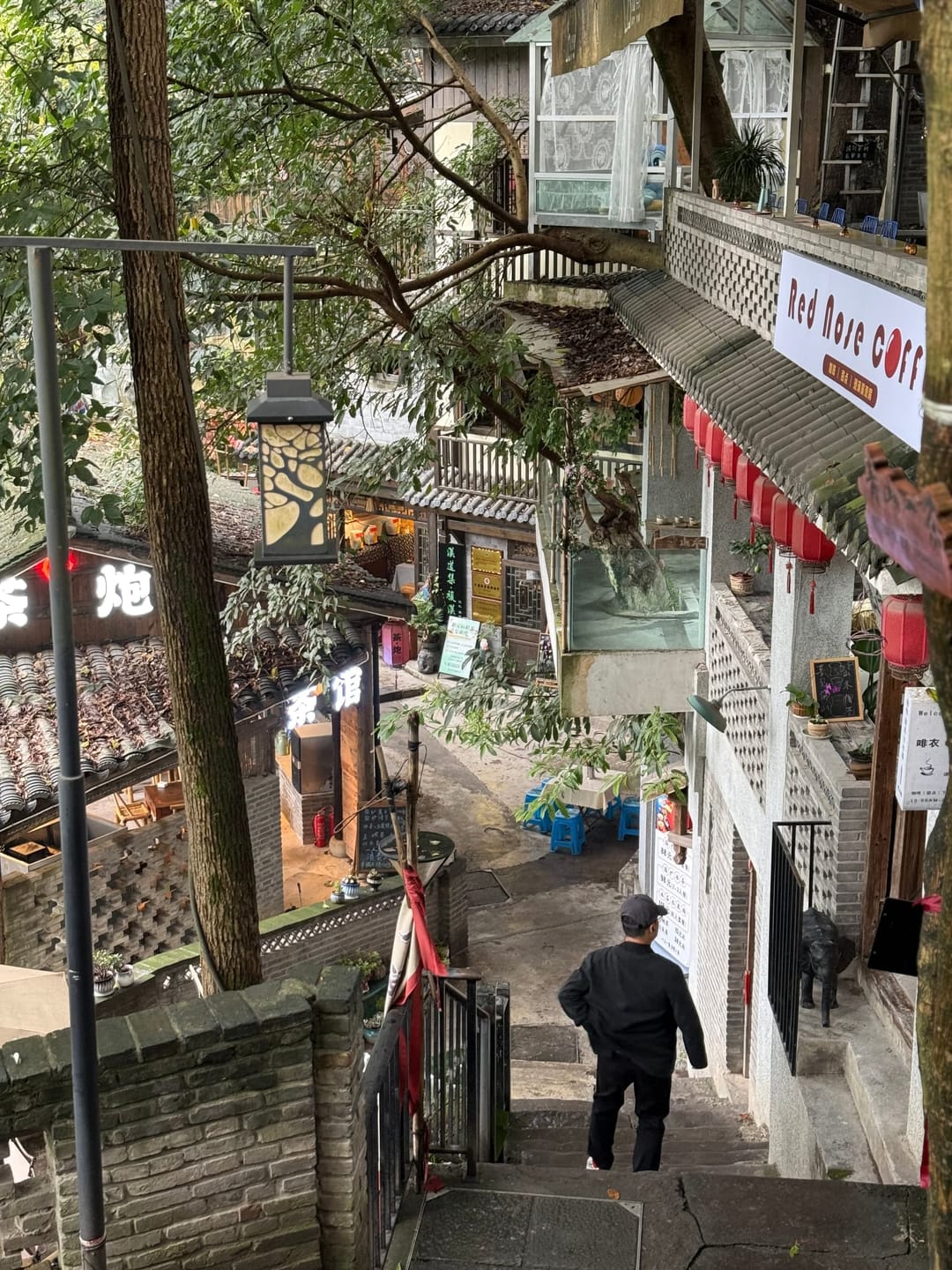 Vue en plongée depuis les marches d'une ruelle de Chongqing, échoppes et passant en contrebas