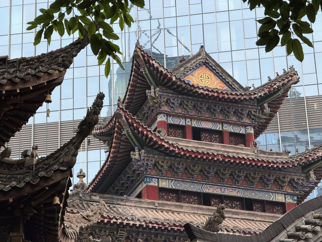 Toitures ornementées d'une pagode traditionnelle se détachant sur la façade de verre d'un gratte-ciel moderne