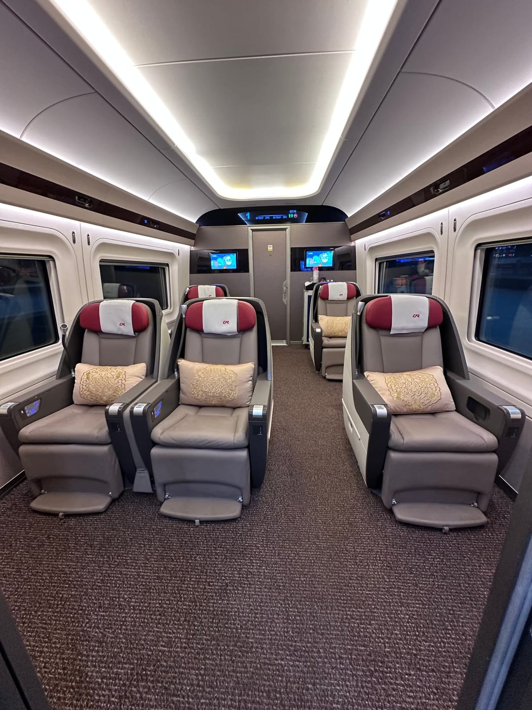Sièges de première classe d'un TGV chinois, larges fauteuils en cuir bordeaux et beige face à face