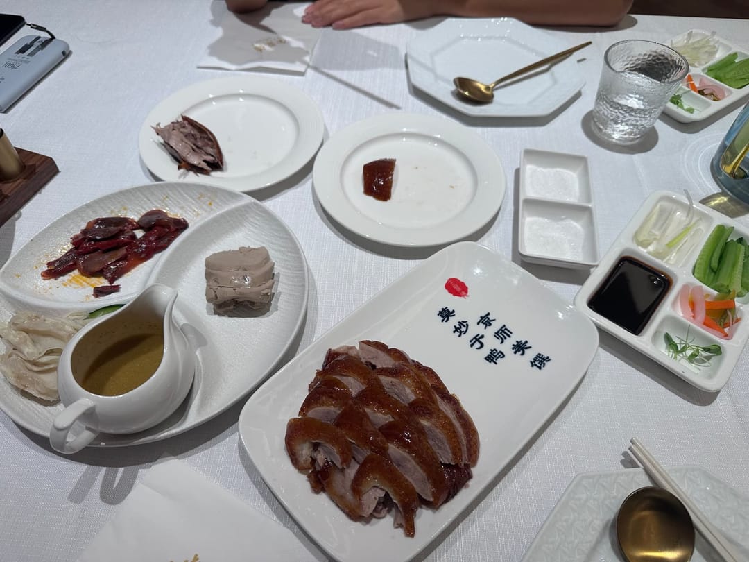 Canard laqué de Pékin découpé sur un plateau, peau croustillante, galettes fines, sauce et bâtonnets de concombre et d'oignon
