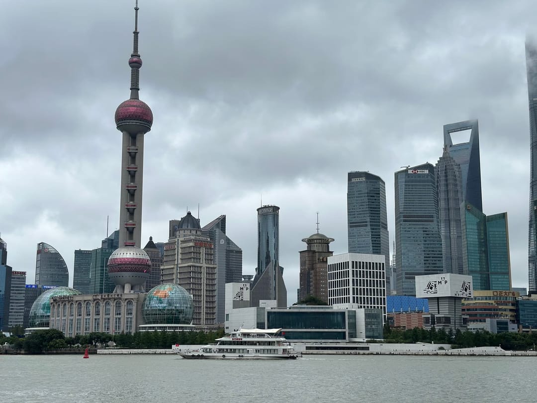 Skyline de Pudong depuis le Bund sous un ciel couvert, un navire blanc remontant le Huangpu au premier plan