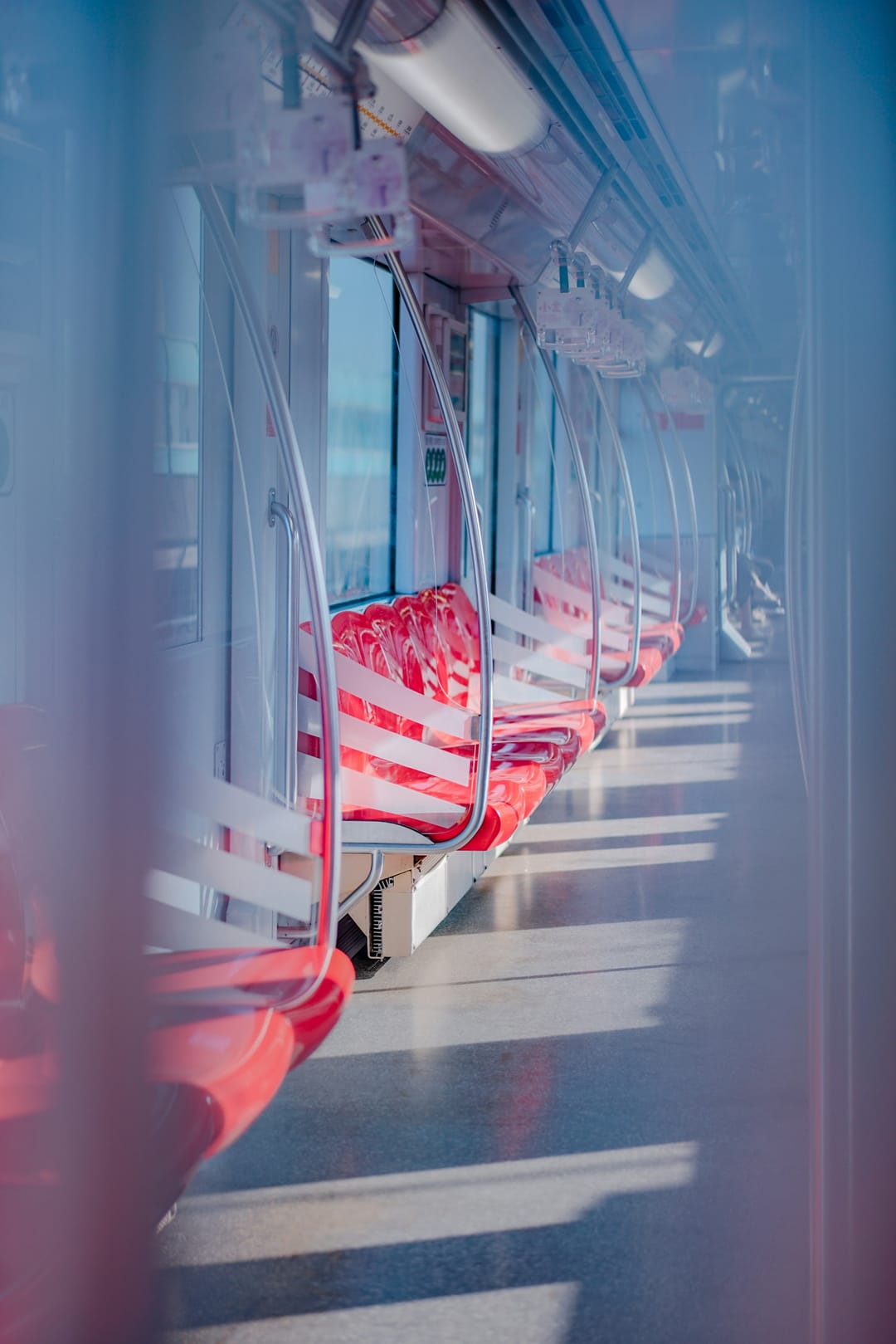 Intérieur d'une rame de métro à Shanghai : sièges rouges vides, barres chromées et sol baigné de lumière