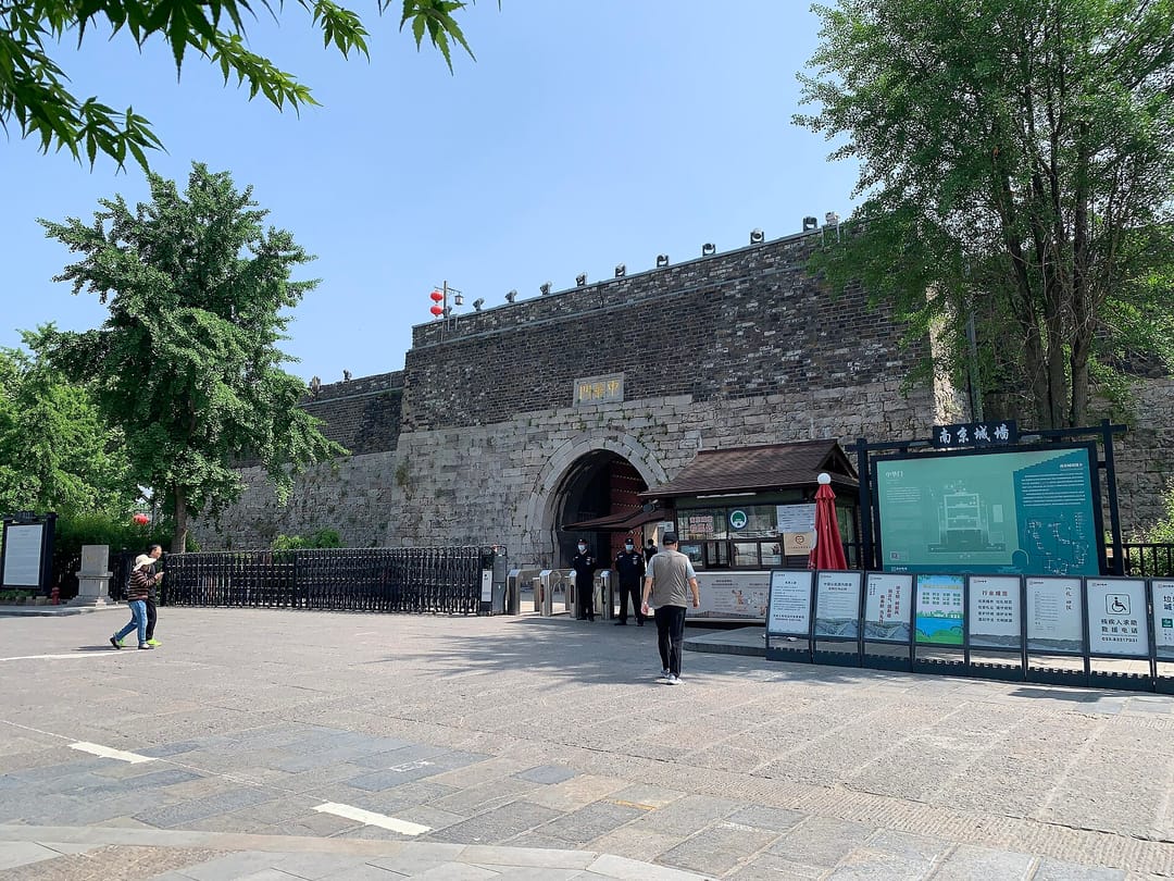 La porte Zhonghua de Nankin vue depuis l'esplanade, mur de brique massif percé d'une arche, panneau explicatif à droite