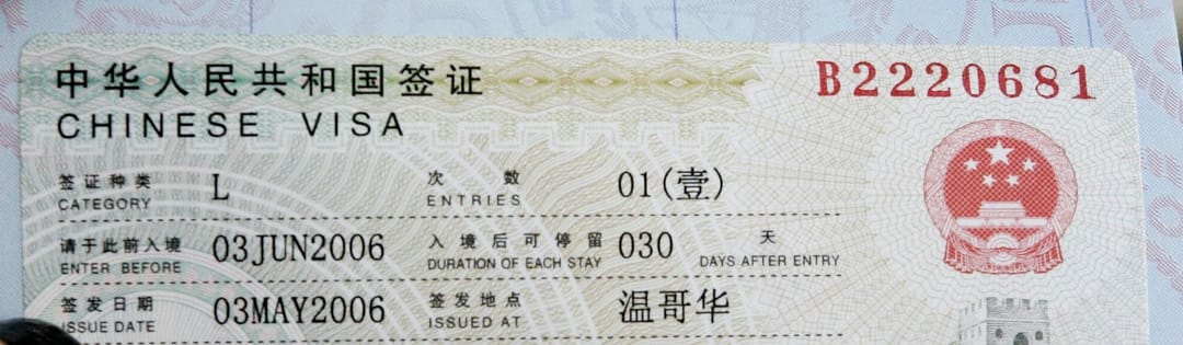 Gros plan d'une vignette de visa chinois collée dans un passeport, portant les mentions CHINESE VISA, catégorie L, une entrée, date limite d'entrée et durée de séjour de 30 jours par entrée