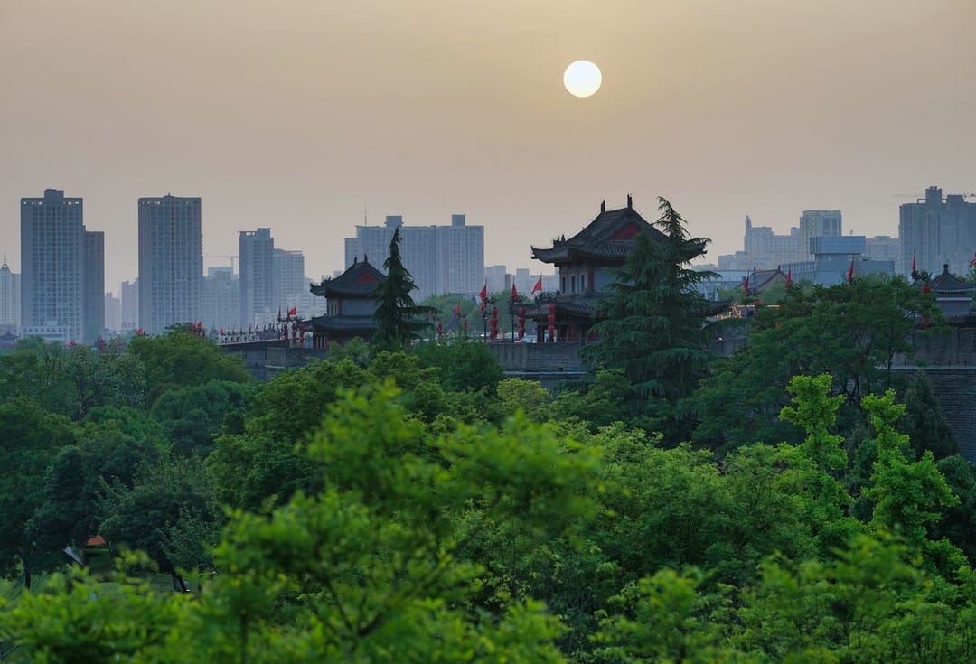 Remparts Ming de Xi'an au crépuscule, pavillon à toit recourbé et lanternes rouges sur la muraille, tours modernes en arrière-plan